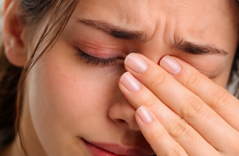 빨갛게 충혈된 눈을 찡그리고 괴로워하는 여자의 얼굴